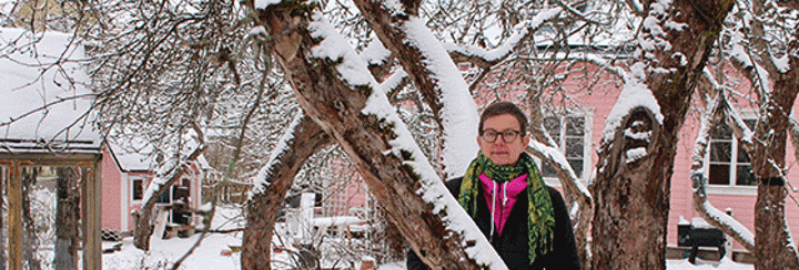 Auli Kukkonen seisoo ulkona kotipihallaan talvisessa maisemassa.